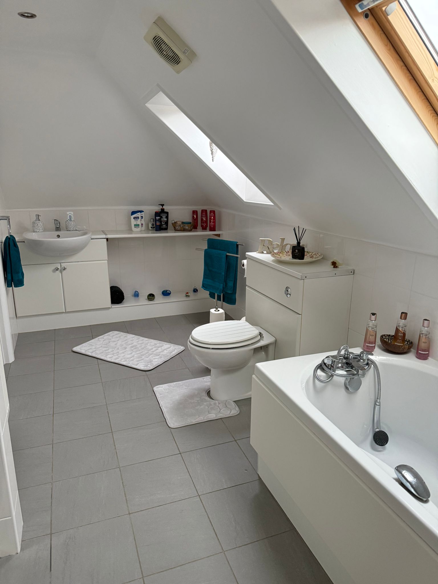 Spacious upper bathroom with bathtub and skylight.