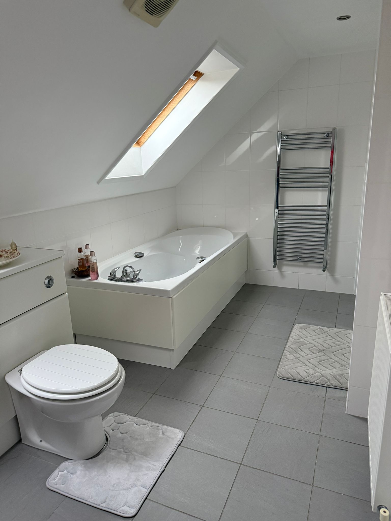 Bathroom with bath, shower, and bright tiled finishes.