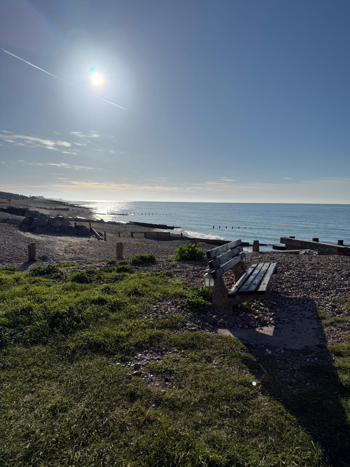 Sunny seafront bench and beach near the property.