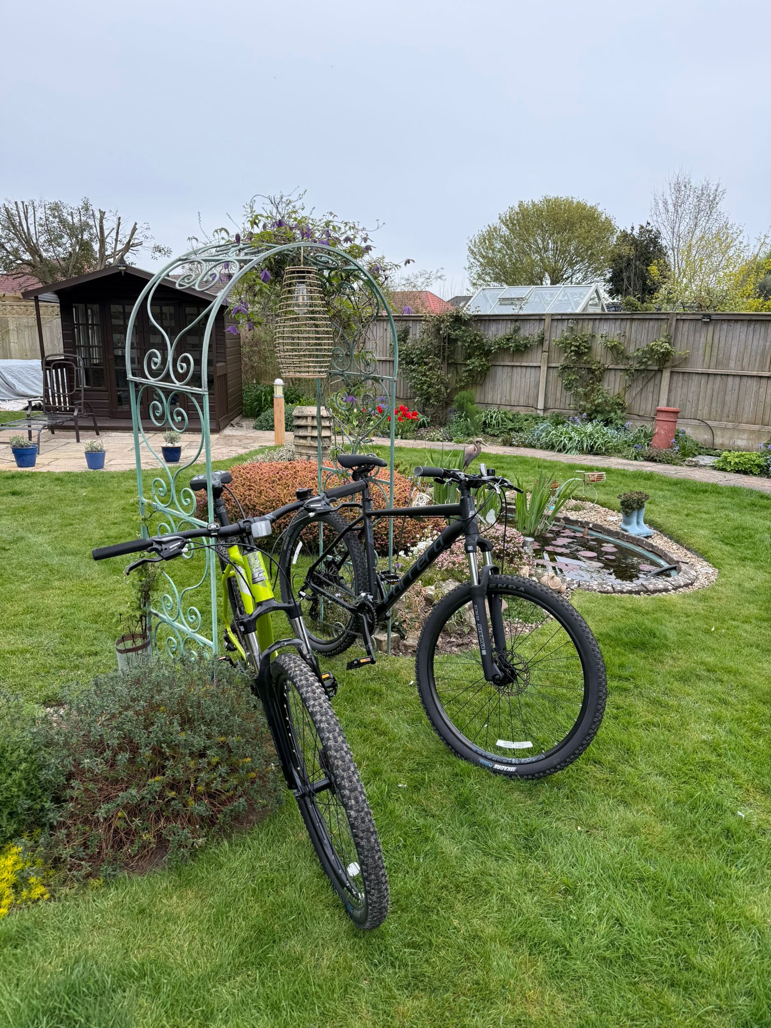 Garden arch with bicycles and landscaped greenery.