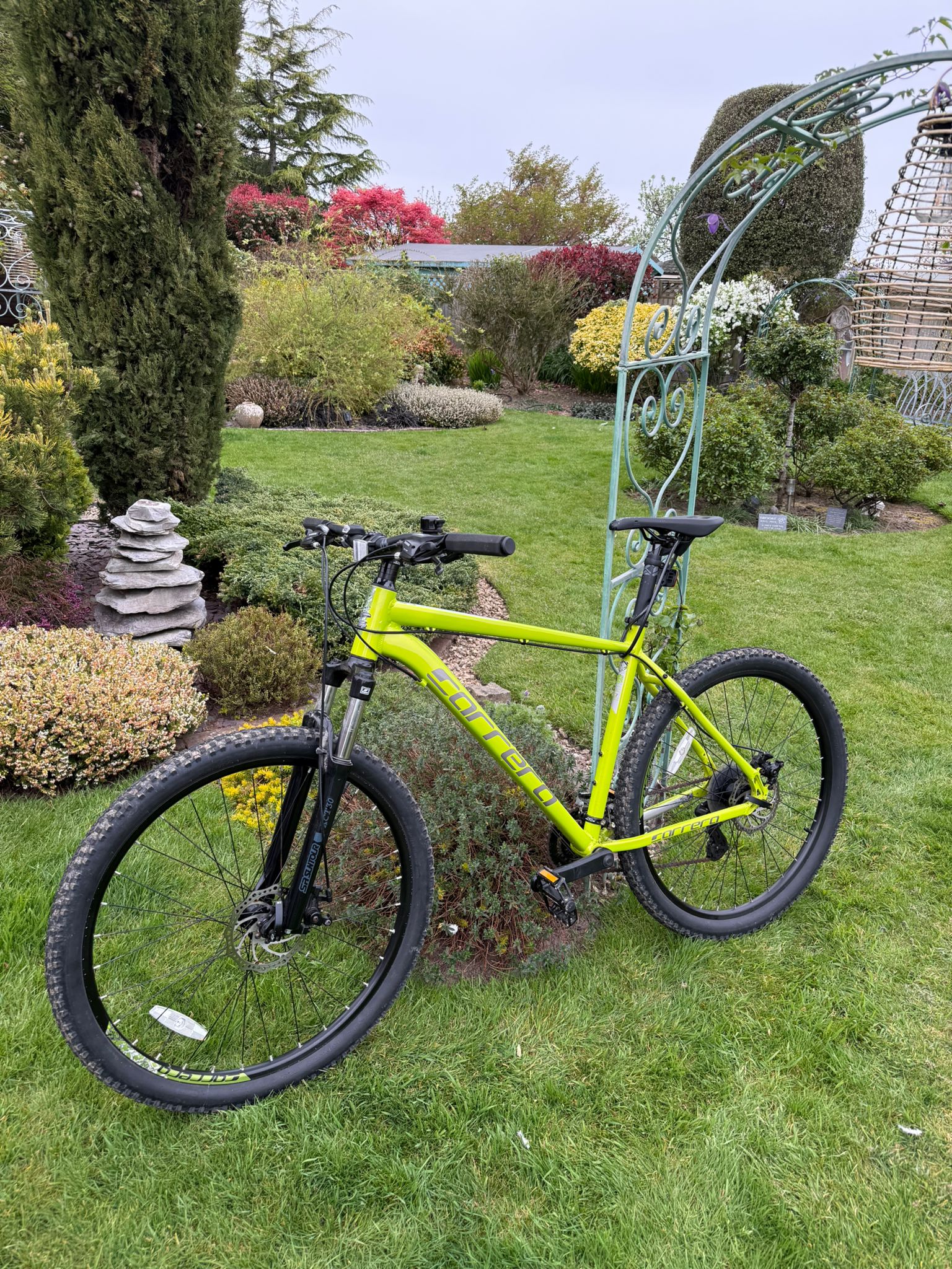 Bright green bike framed by the garden arch.