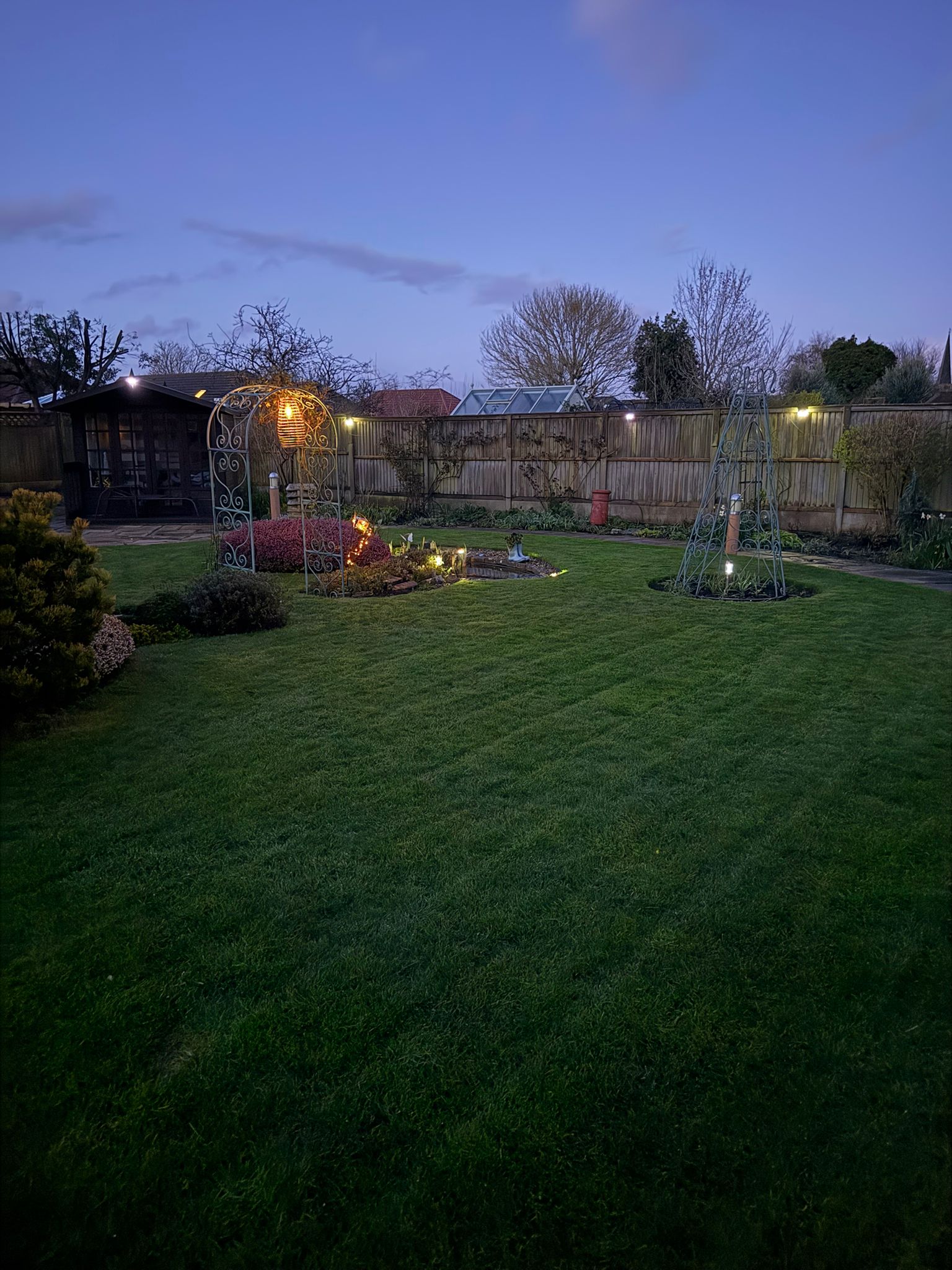 Wide evening view of the illuminated garden.