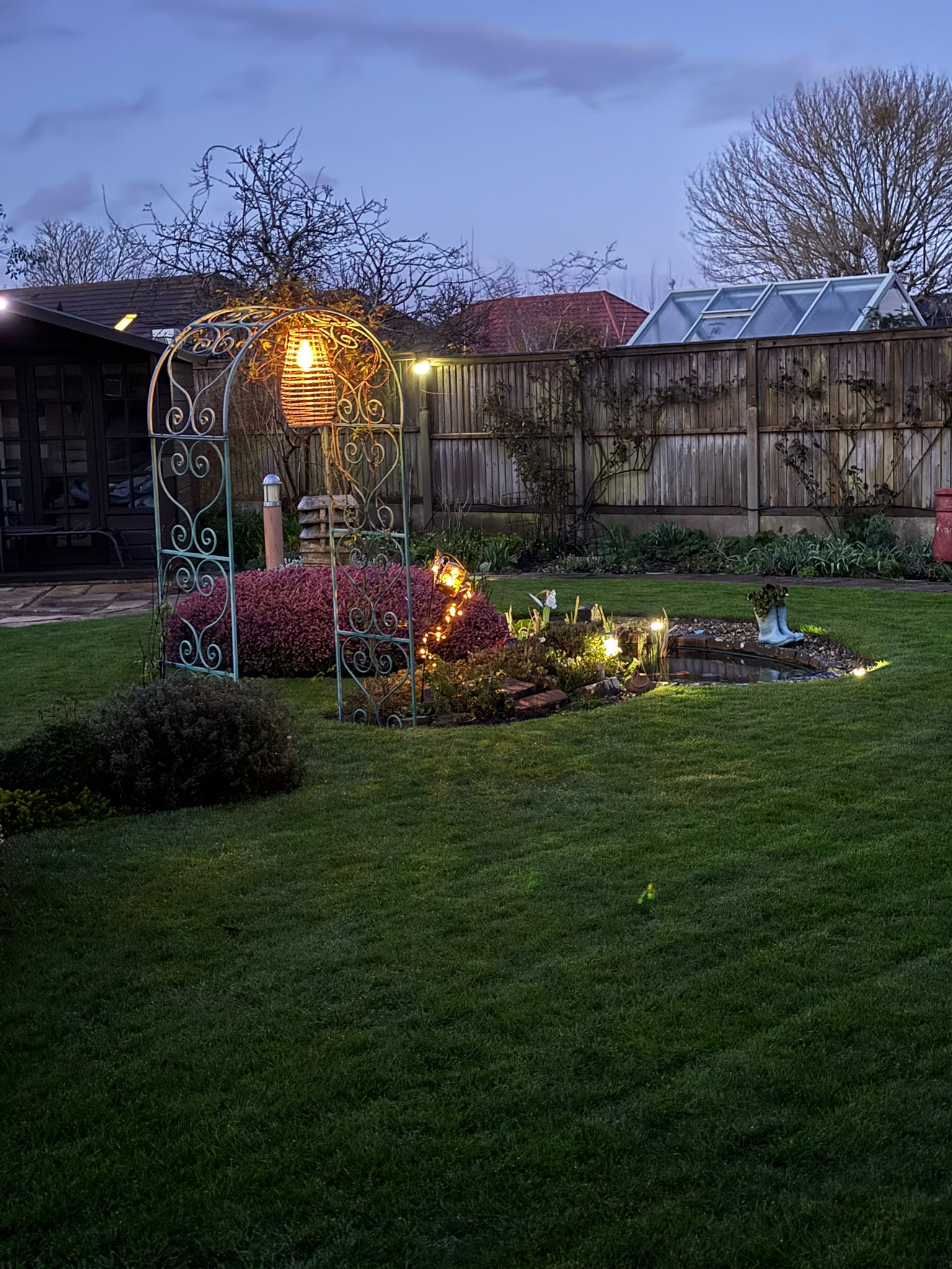 Evening garden feature with warm lights near the pond.